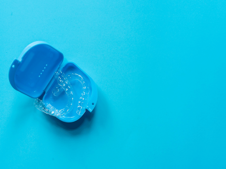 two clear aligners inside a case on a teal background
